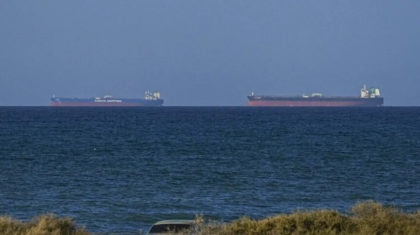 Dva velika teretna broda plove mirnim tamnoplavim morem pod vedrim plavim nebom. Jedan brod, označen natpisom 'COSCO SHIPPING', vidljiv je na lijevoj strani kadra.
