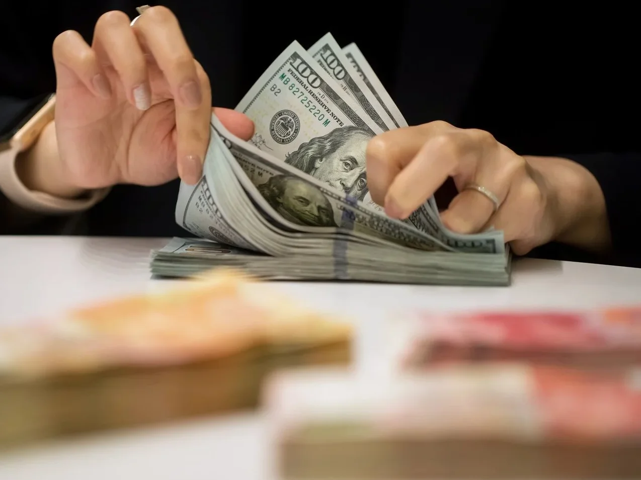 Ruka koja broji novčanice od 100 američkih dolara