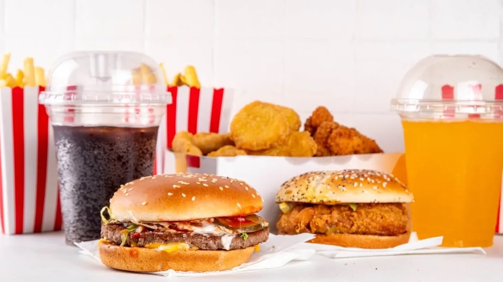 Dva ukusna hamburgera, pomfrit, pileći nuggetsi i dva osvježavajuća pića, tamni gazirani sok i narandžasti sok.