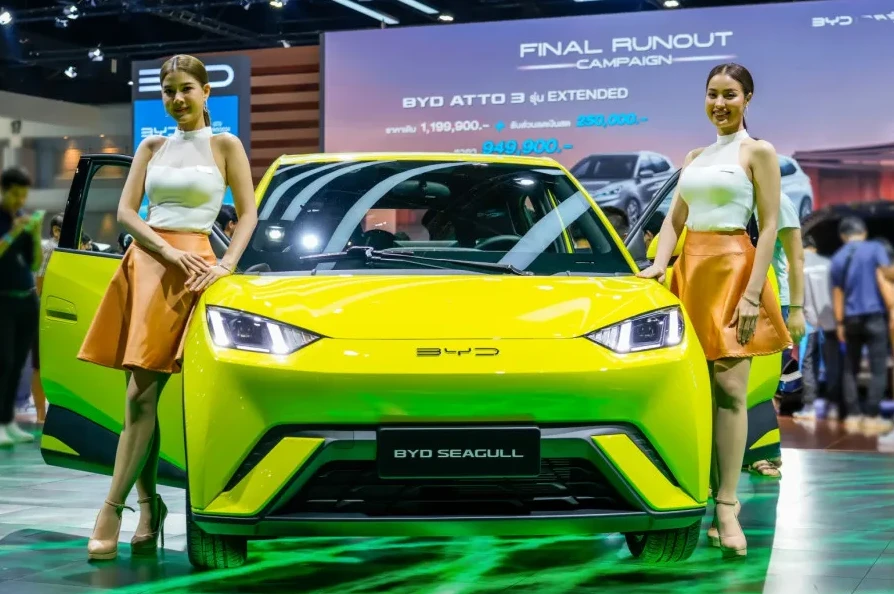 Dvije žene stoje pored jarko žutog BYD Seagull automobila na sajmu automobila.