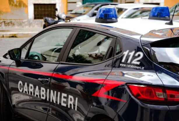 Tamni automobil italijanske policije, poznate kao Karabinijeri, sa crvenim detaljima i svijetlećim plavim rotacijama na krovu.
