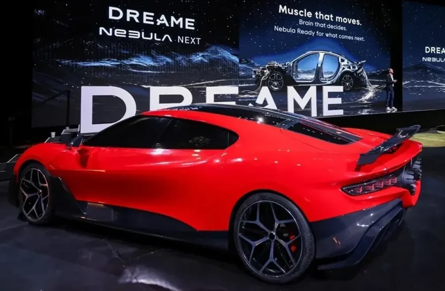 Crveni sportski automobil marke "DREAM • NEBULA NEXT" prikazan na pozornici.