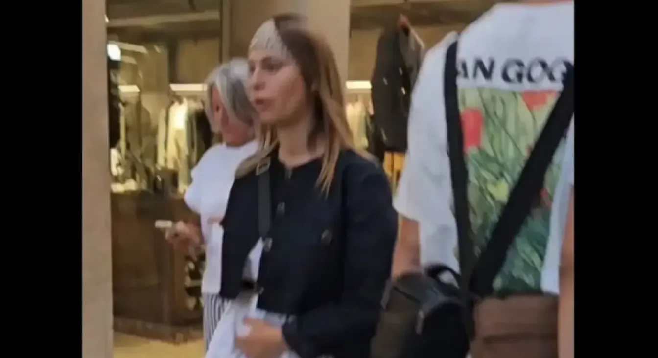 Žena u crnom sakou i sa maramom na glavi na ulici.