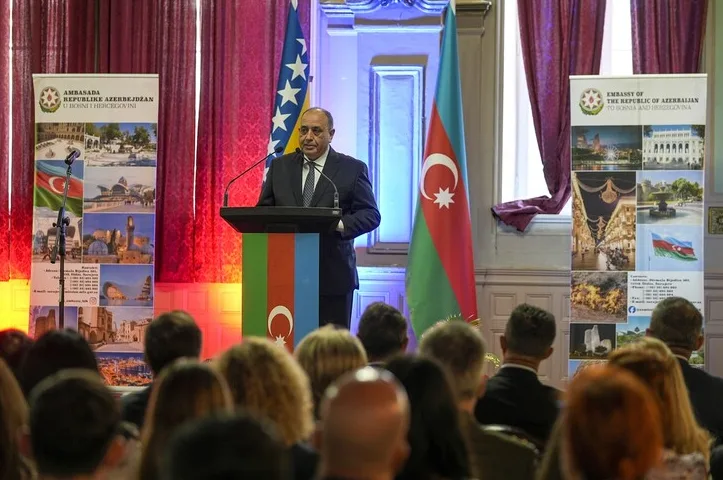 Predavač govori za govornicom ispred zastava Azerbejdžana i Bosne i Hercegovine na diplomatskom skupu.