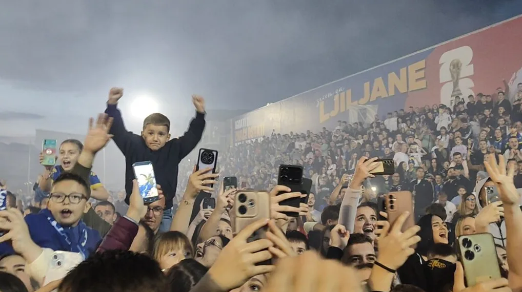 Djeca slave na stadionu, držeći mobitele i slikajući