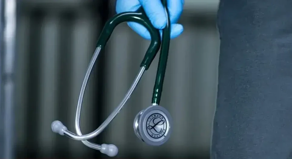 Ljekar u plavim rukavicama drži medicinski stetoskop.