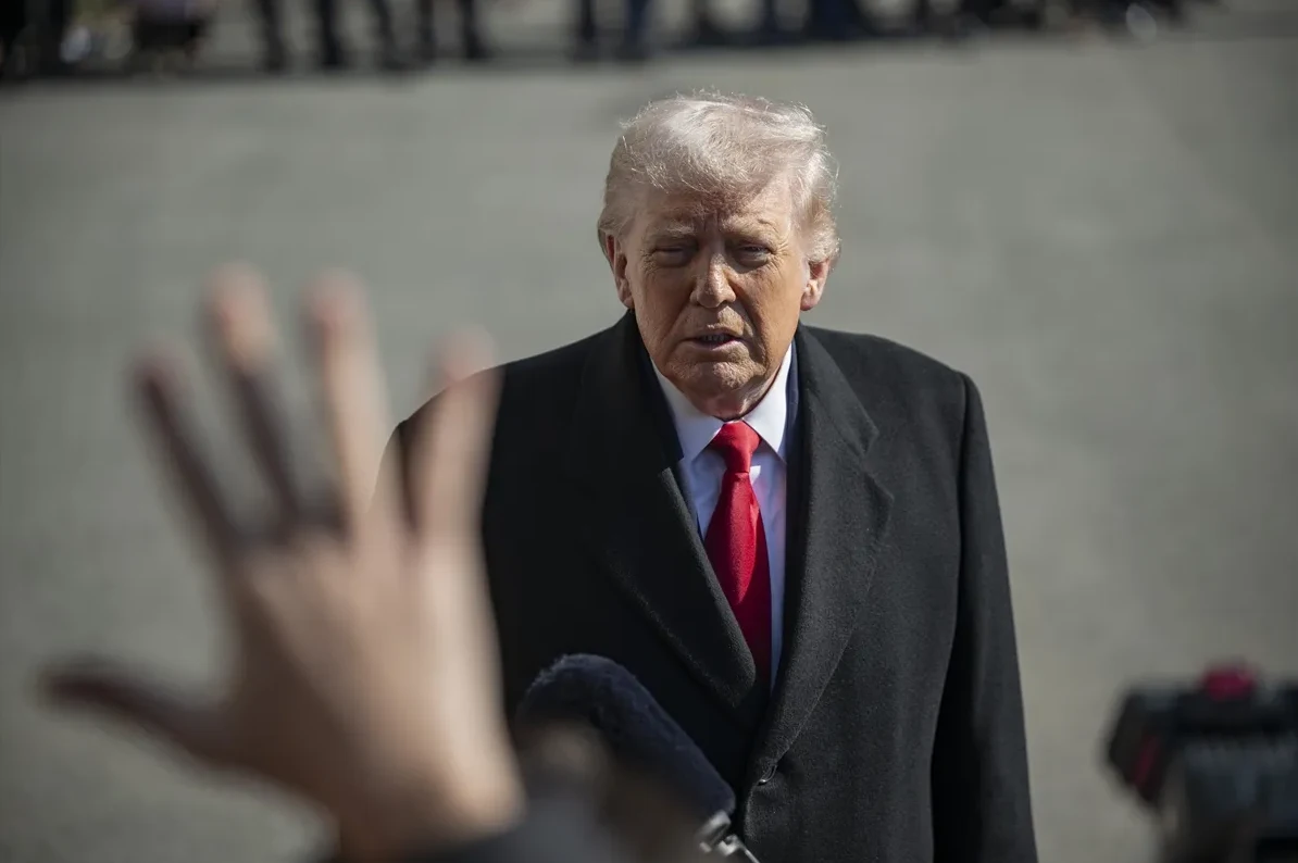 Donald Tramp sa crvenom kravatom i crnim kaputom suočen sa novinarom koji drži mikrofon i ispružio je ruku.