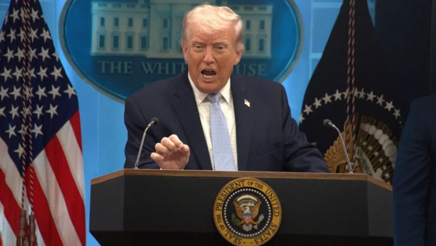 Donald Trump govori iza podijuma u Bijeloj kući sa američkom zastavom i pečatom predsjednika Sjedinjenih Država.