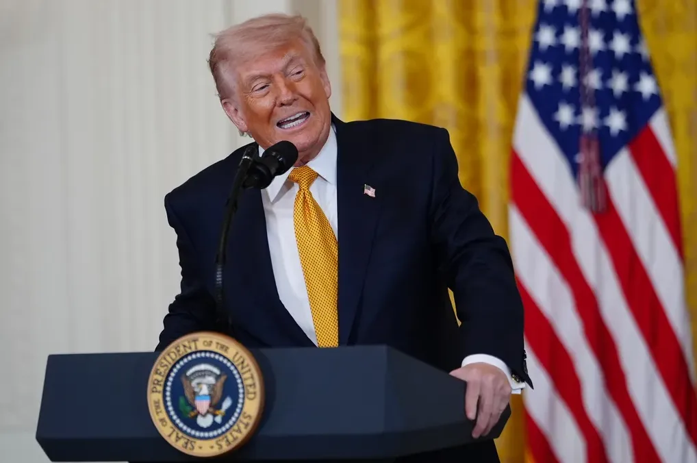 Donald Trump govori iz govornice sa znakom "President of the United States" i Američkom zastavom u pozadini.