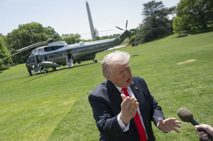 Donald Trump govori u mikrofon, sa helikopterom u pozadini.