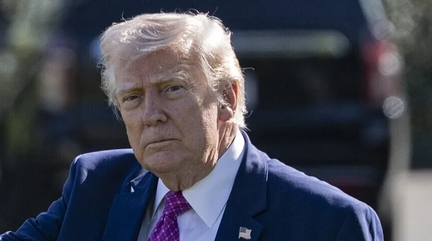 Donald Trump u plavom sakou i ljubičastoj kravati sa američkom zastavicom na reveru.