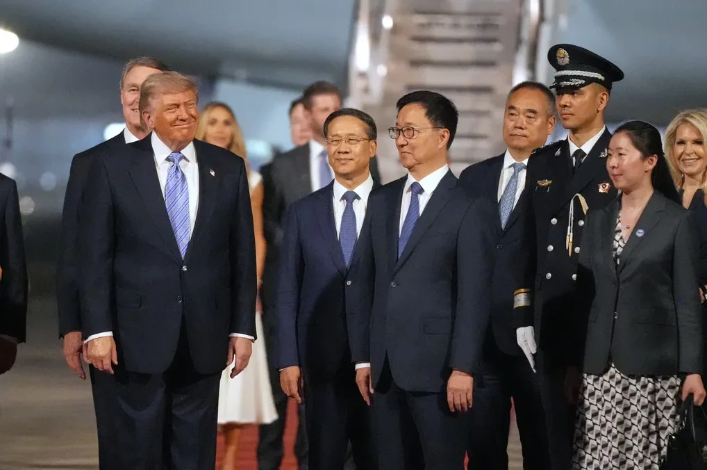 Donald Trump se smiješi dok stoji pored grupe kineskih zvaničnika.