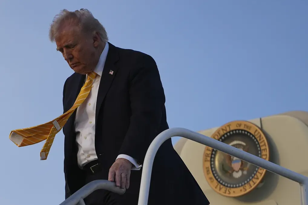 Donald Trump silazi stepenicama aviona sa zaljuljanom žutom kravatom.