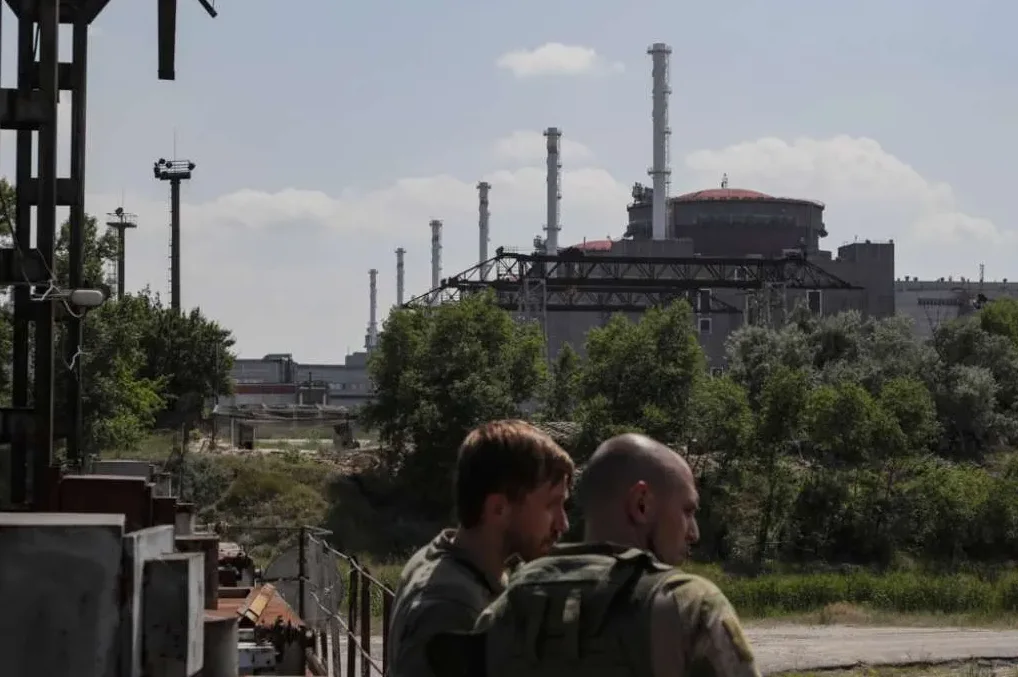 Dva vojnika u vojnim uniformama stoje ispred nuklearne elektrane Zaporožje.