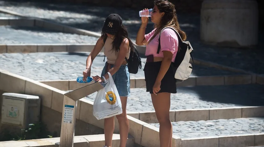 Dvije djevojke piju vodu iz plastičnih boca tokom vrućeg dana.