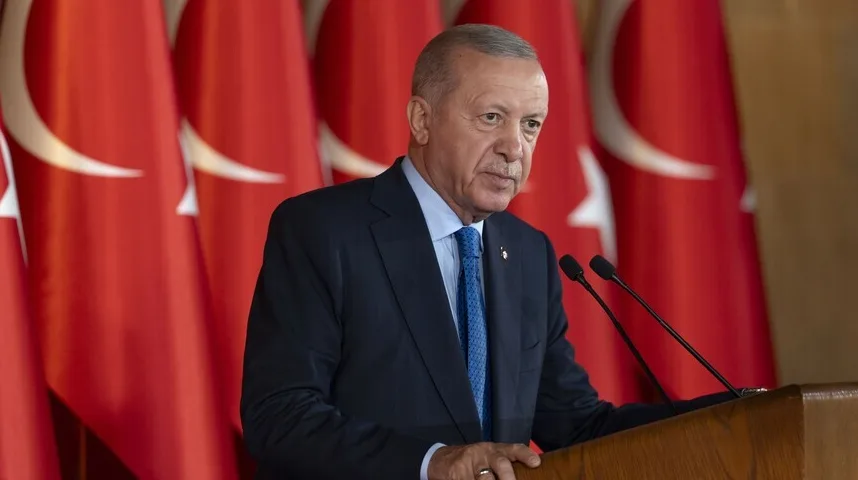 Recep Tayyip Erdoğan govori iza govorničkog podijuma sa turskim zastavama u pozadini.
