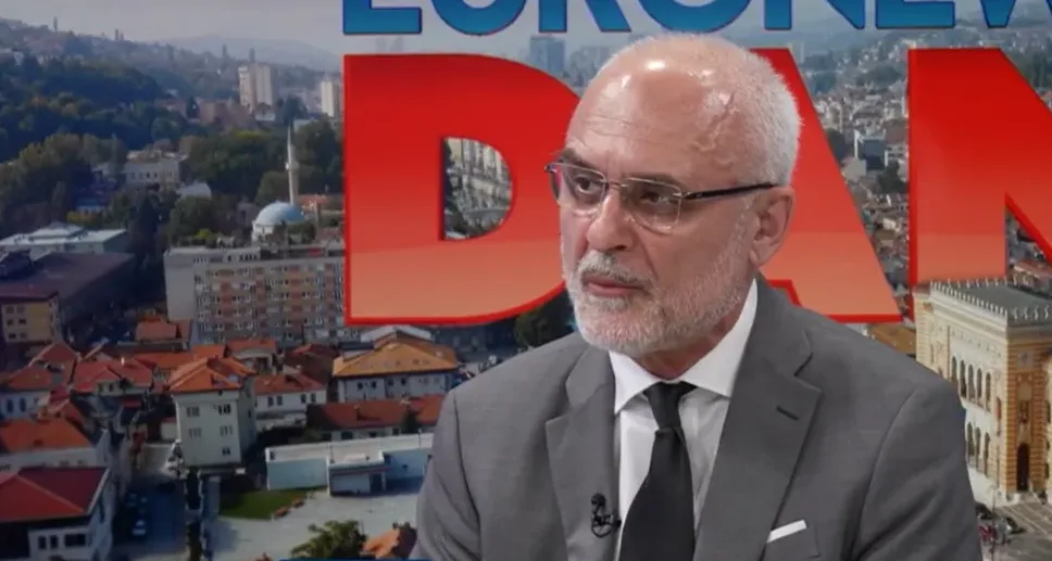 Muškarac u odijelu sa naočalama i bradom, sjedi u studiju, sa logom "EURO NEWS DAN" u pozadini.