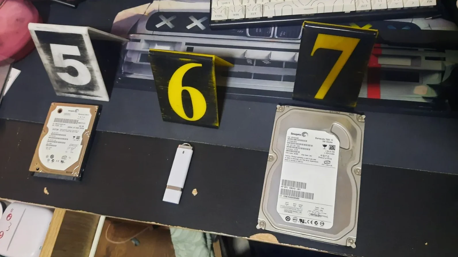 Tri brojevne oznake (5, 6, 7) i tri uređaja za skladištenje podataka (hard disk, USB memorija, hard disk).