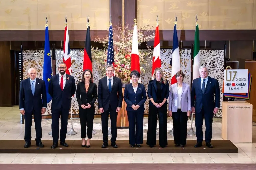 Grupa G7 ministara vanjskih poslova pozira za grupnu fotografiju ispred zastava svojih zemalja na samitu u Hirošimi 2023. godine.