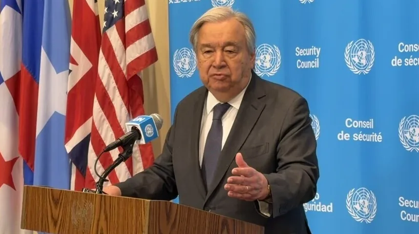 António Guterres, generalni sekretar Ujedinjenih naroda, govori iza govornice sa zastavama.