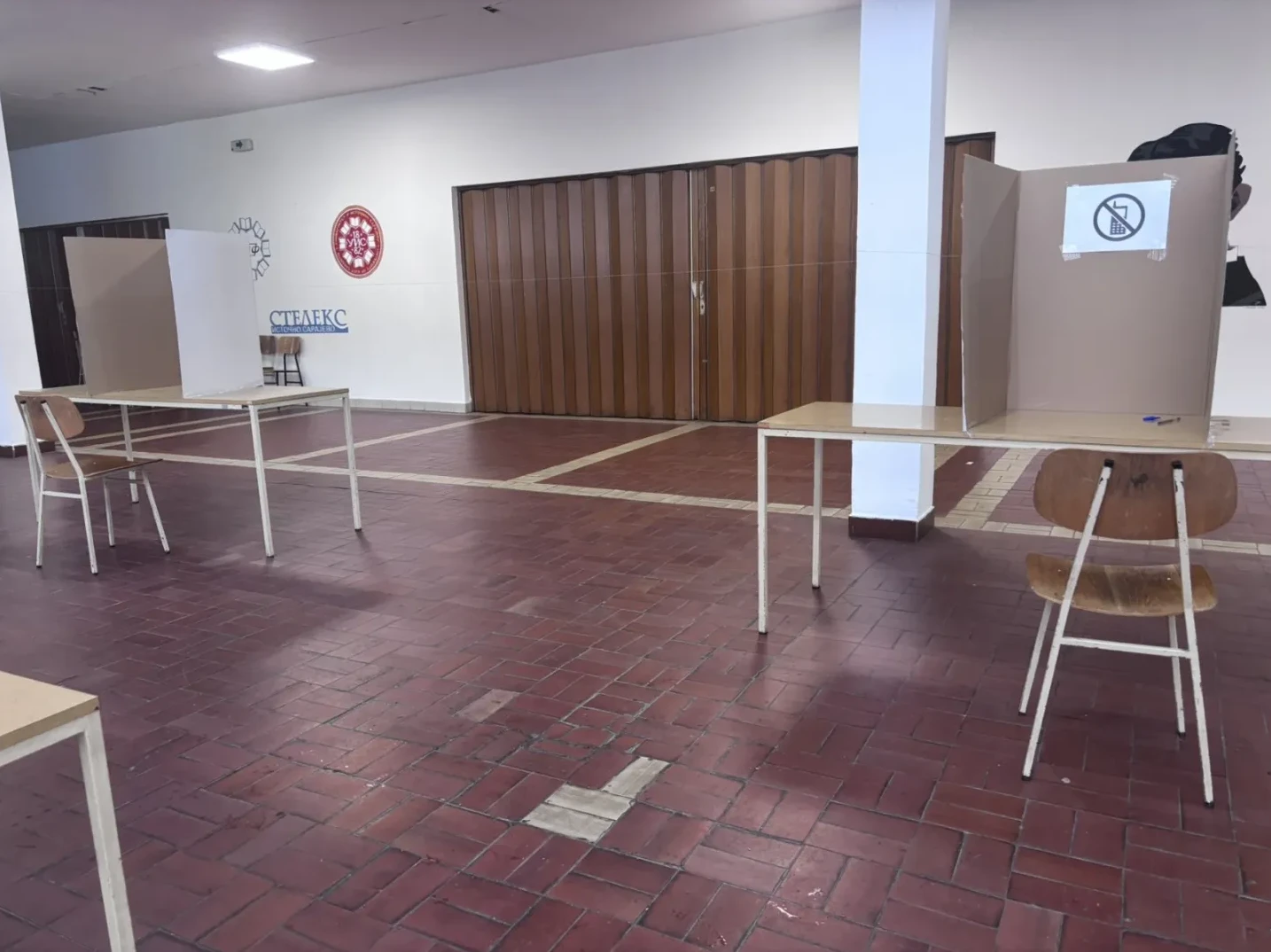 Izborni štandovi sa stolovima i stolicama u praznoj prostoriji.