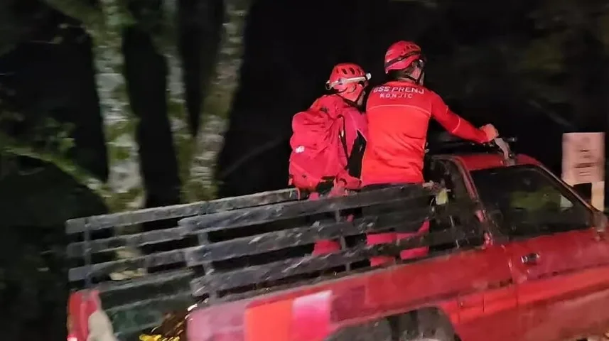 Dva člana Gorske službe spasavanja Konjic u crvenim uniformama i kacigama, od kojih jedan nosi ruksak, voze se u tovarnom prostoru crvenog teretnog vozila.