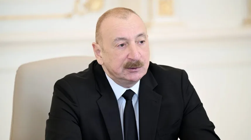 Predsjednik Ilham Alijev sjedi u crnom odijelu i bijeloj košulji sa crnom kravatom.