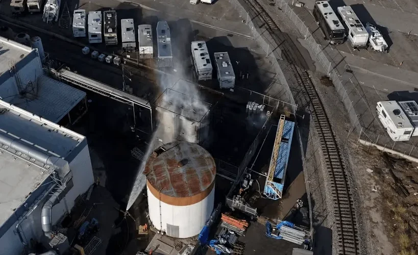 Nadzemni prikaz industrijskog skladišta s brojnim prikolicama i vozilima za odmor parkiranim na asfaltiranom terenu.