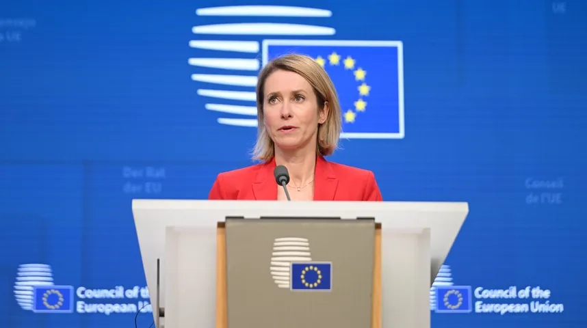 Kaja Kallas, premijerka Estonije, u crvenom sakou, obraća se sa podijuma ispred zastave Evropske unije.