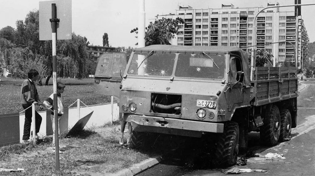 Kamion sa tragovima granatiranja i dvoje dječaka pored puta