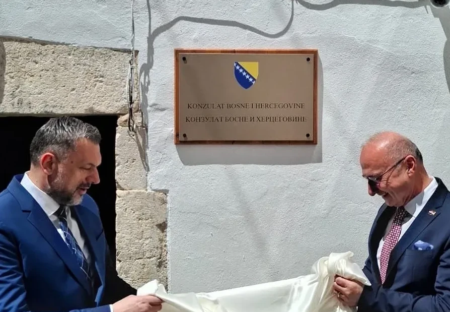Otkrivanje ploče sa grbom Bosne i Hercegovine i natpisom "Konzulat Bosne i Hercegovine" na bijelom zidu.