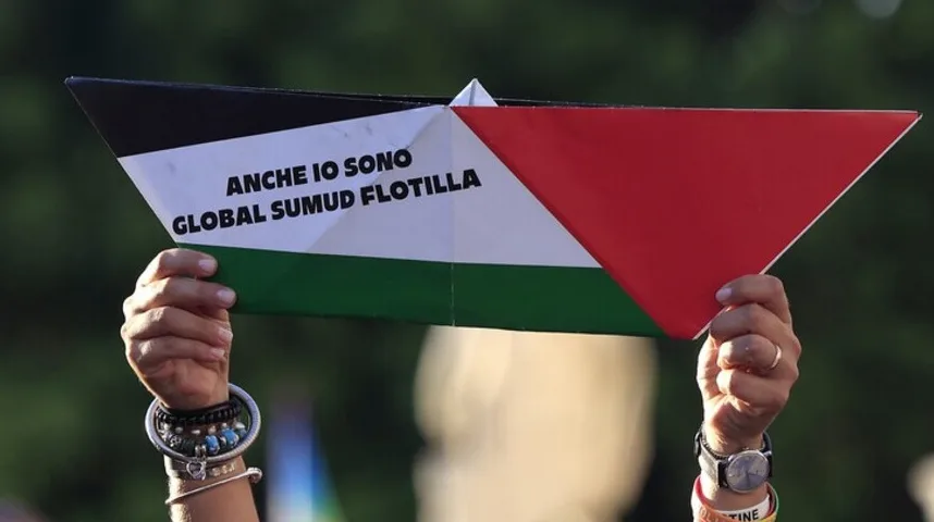 Osoba drži papirni brod oslikan palestinskom zastavom sa natpisom na italijanskom: "Anche io sono global sumud flotilla"