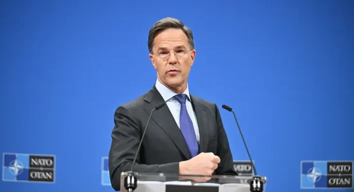 Mark Rutte drži govor iza govornice s logom NATO-a u pozadini.
