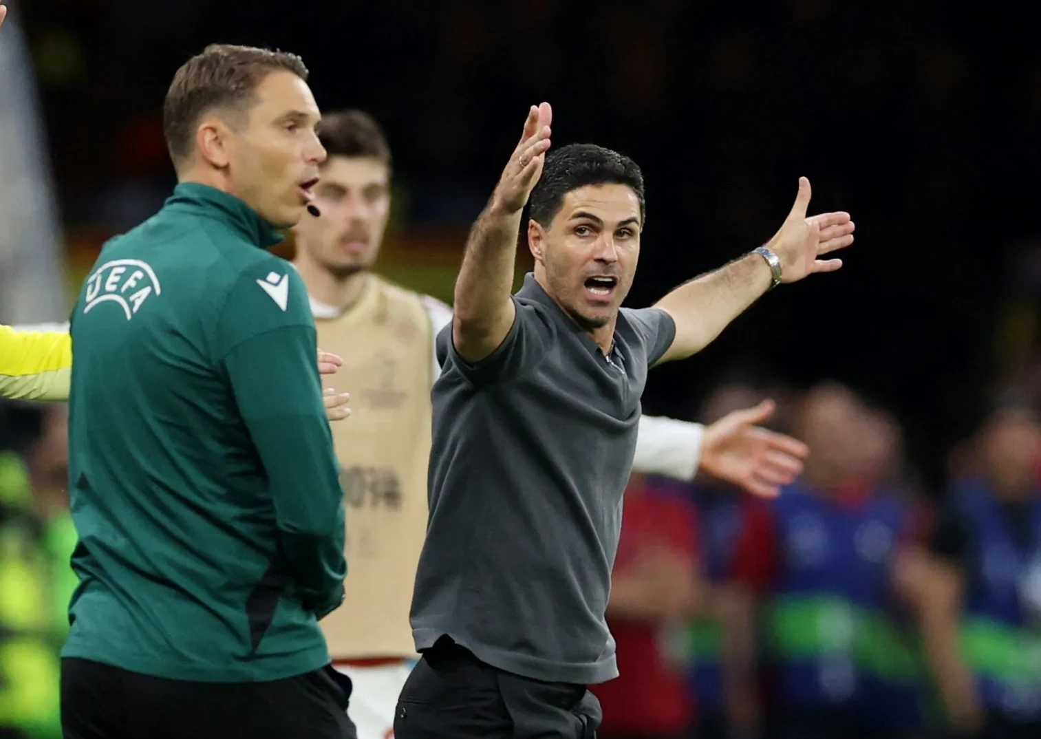 Trener Arsenala Mikel Arteta sa gestikulacijom ruku pokazuje nezadovoljstvo odlukom sudije na evropskoj fudbalskoj utakmici, dok sudija u zelenom dresu nosi oznaku UEFA.