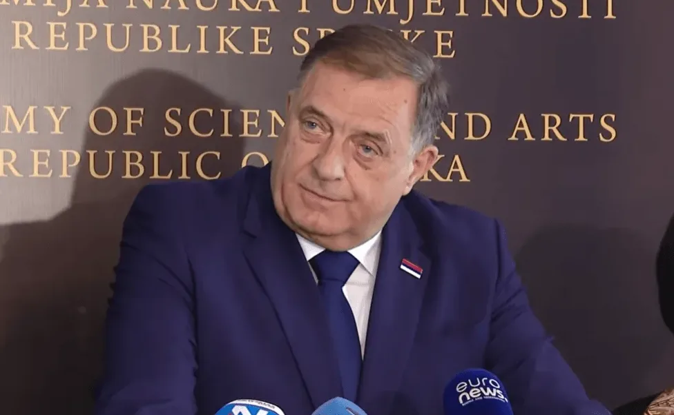 Milorad Dodik nosi plavo odijelo i kravatu, sa zastavicom Republike Srpske na reveru.