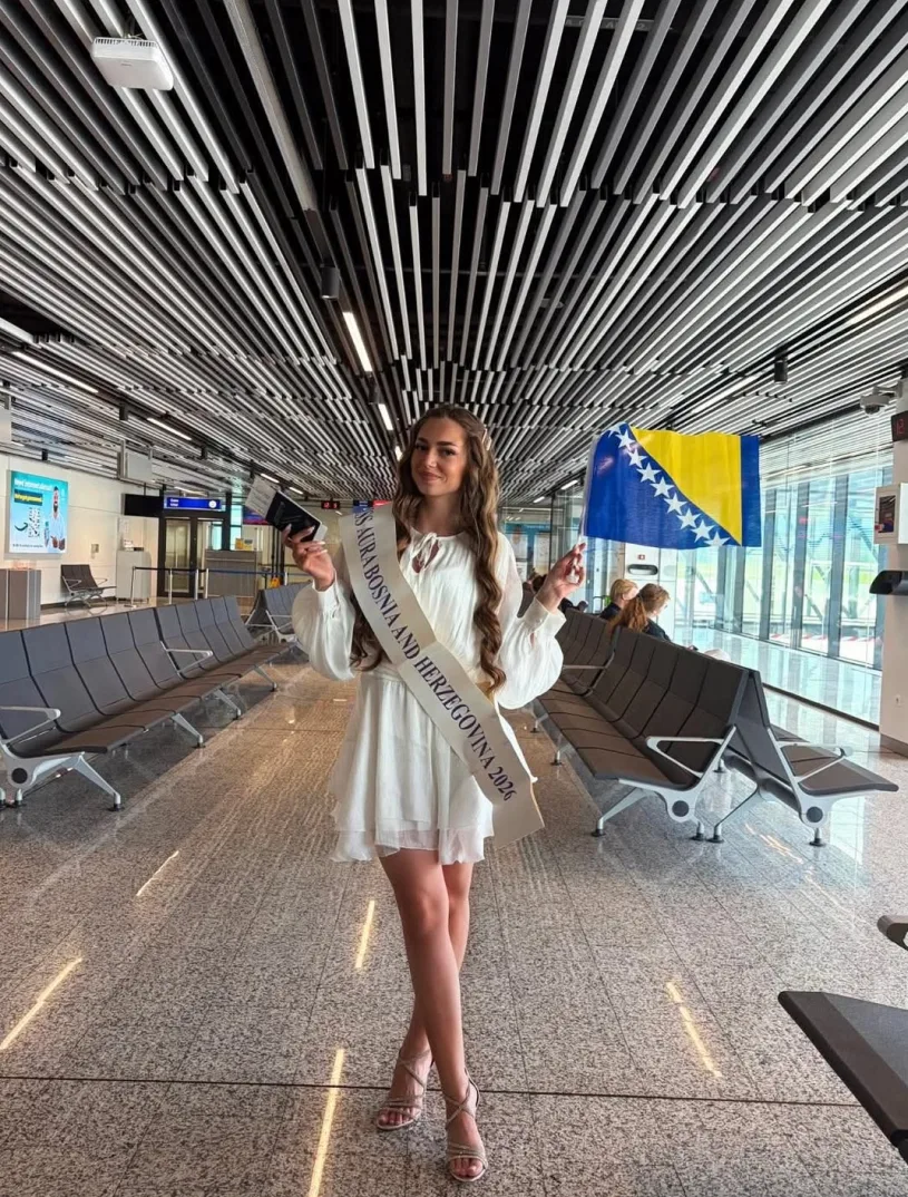 Djevojka sa trakom "Miss Aura Bosne i Hercegovine 2026" i zastavom BiH na aerodromu.
