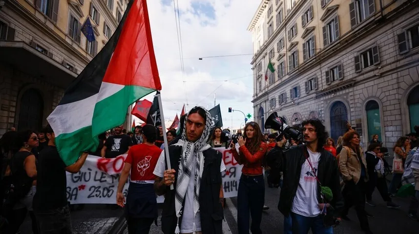 Demonstranti marširaju ulicom noseći palestinsku zastavu i transparente, neki od učesnika nose i palestinske marame (keffiyeh).