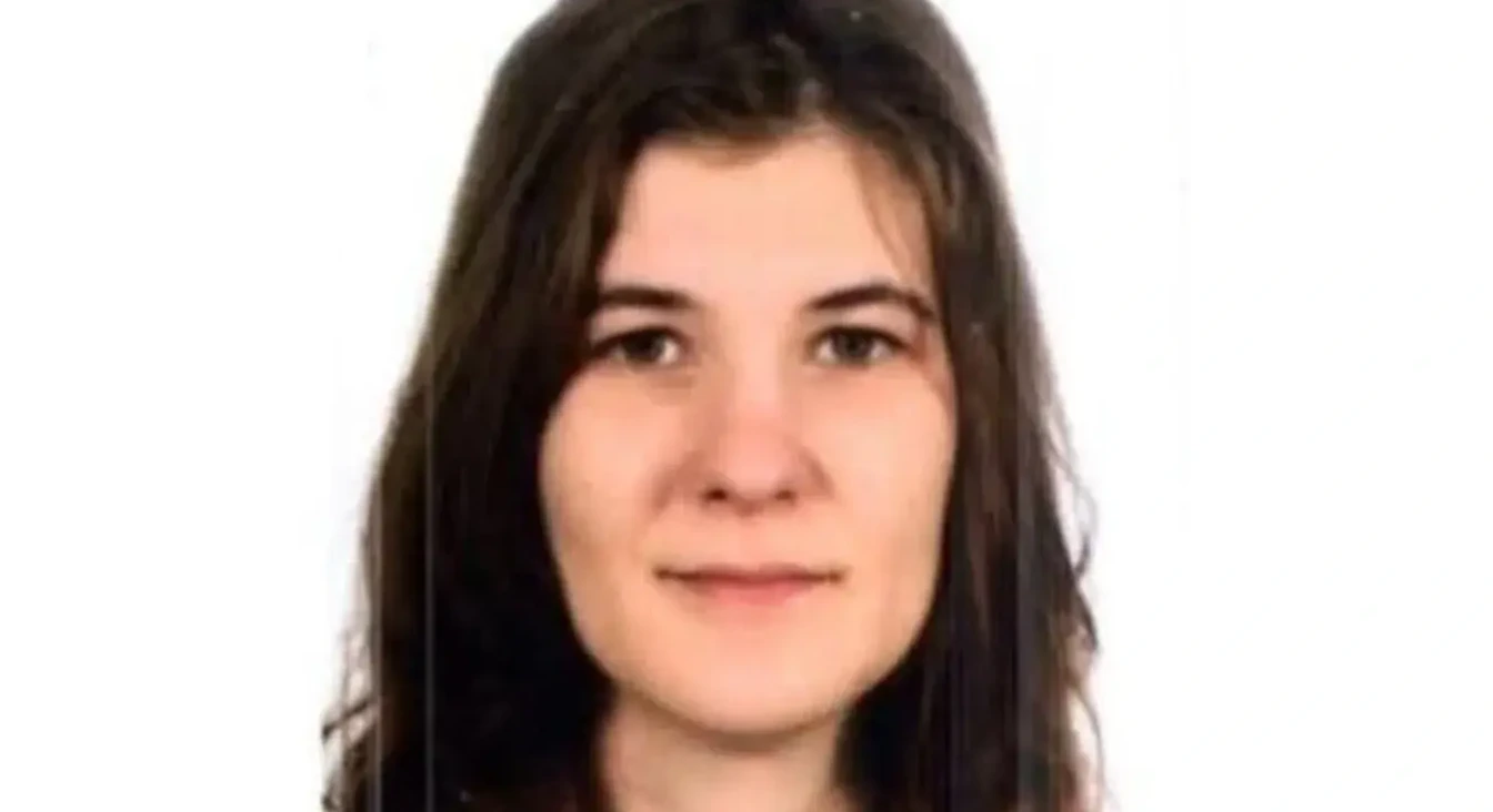 Portret mlade djevojke sa tamnom, valovitom kosom, bijelom pozadinom.