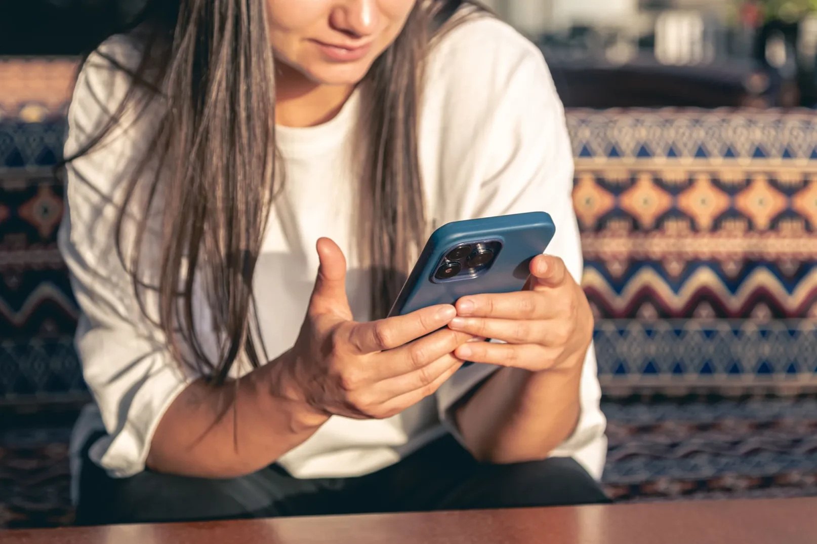 Mlada žena u bijeloj majici koristi pametni telefon.