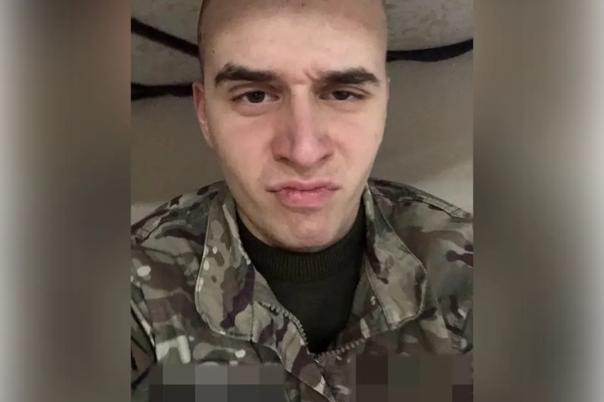 Mladić u vojnoj uniformi sa kratkom kosom i namrštenim izrazom lica.