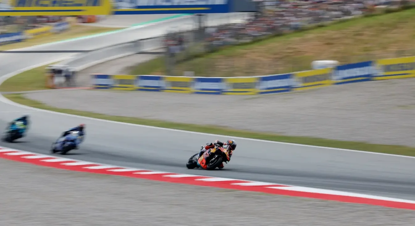 Trojica motociklista u punoj brzini voze se uz krivinu na trkačkoj stazi.