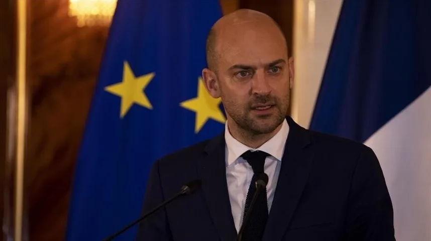 Muškarac u tamnom odijelu s bijelom košuljom i tamnom kravatom, stoji ispred zastave Evropske unije.