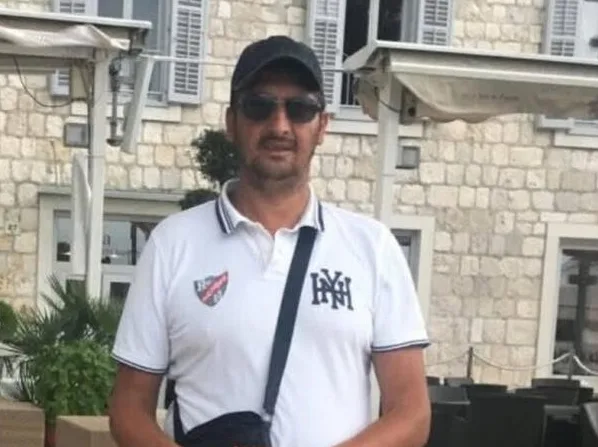 Muškarac u bijeloj polo majici sa tamnim printom i kačketom