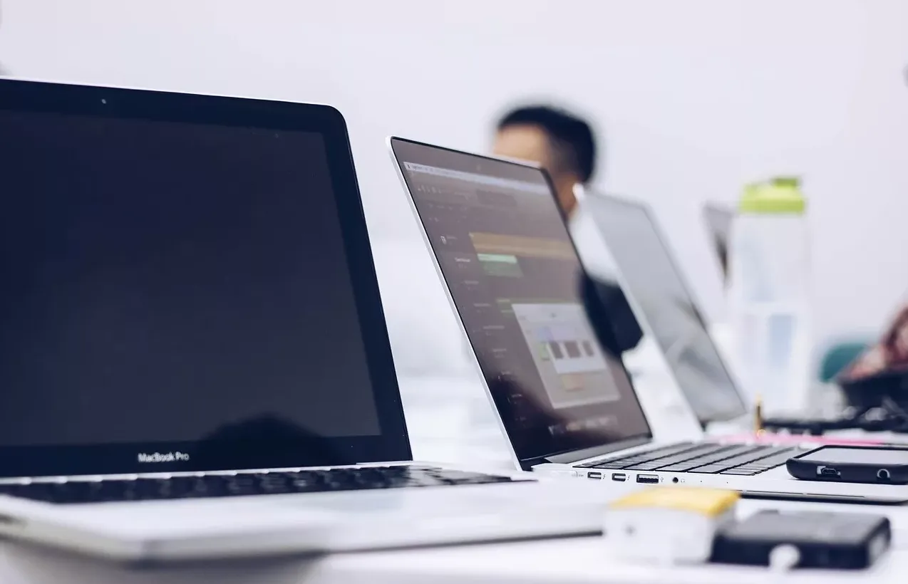 Više otvorenih laptopa na radnom stolu, spremni za upotrebu.