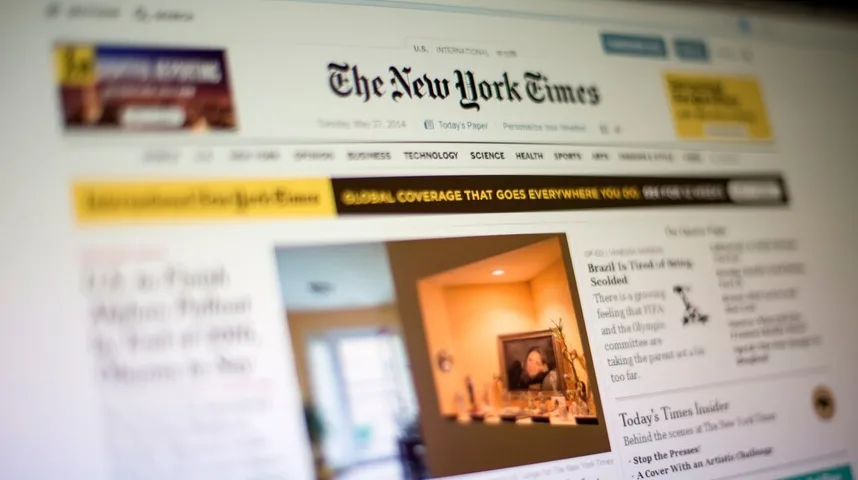 Prikaz naslovne stranice "The New York Times" na ekranu računara, prikazujući naslove i slike članaka, s naglaskom na "Global Coverage That Goes Everywhere You Go".
