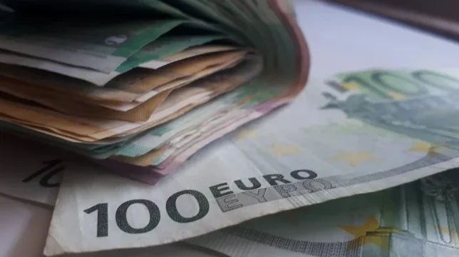 Krupni kadar hrpe novčanica eura, sa naglaskom na novčanicu od 100 eura u prvom planu.