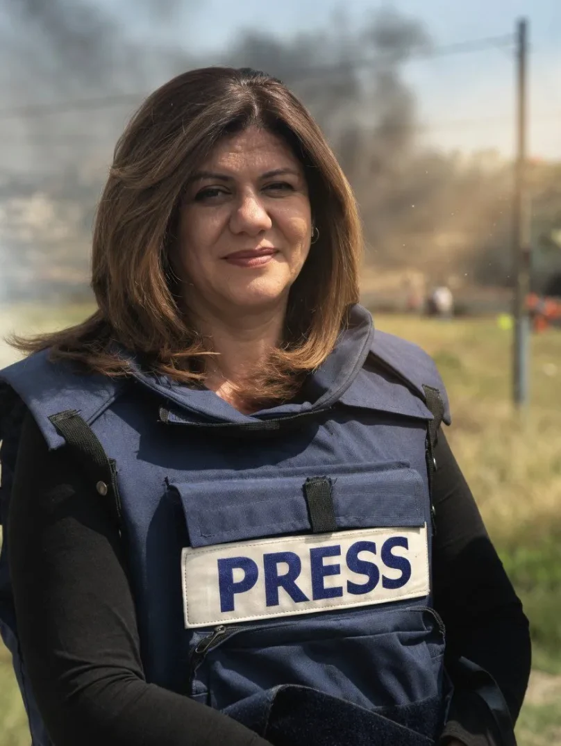Novinarka u pancirnom prsluku s natpisom "PRESS" ispred zamućenog dima