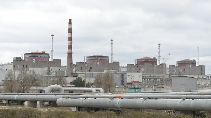 Široki kadar nuklearne elektrane Zaporižžja, koja prikazuje nekoliko reaktorskih zgrada sa crvenim kupolama i brojevima 3, 4, 5 i 6, te nekoliko dimnjaka i kompleksnih sistema cijevi u prvom planu.