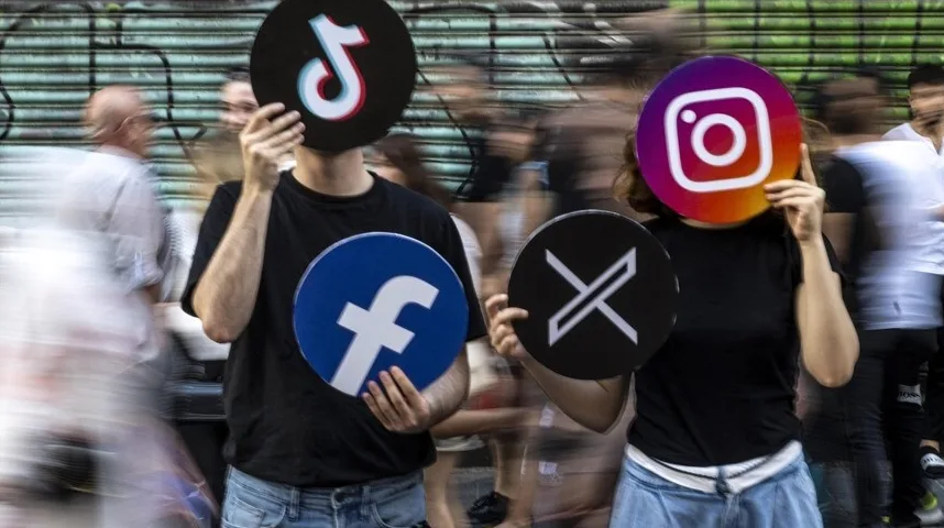 Dvoje ljudi drži okrugle znakove popularnih društvenih mreža ispred svojih lica.