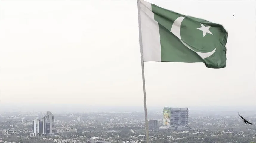 Pakistanska zastava na vjetru iznad panorame grada sa modernim zgradama.
